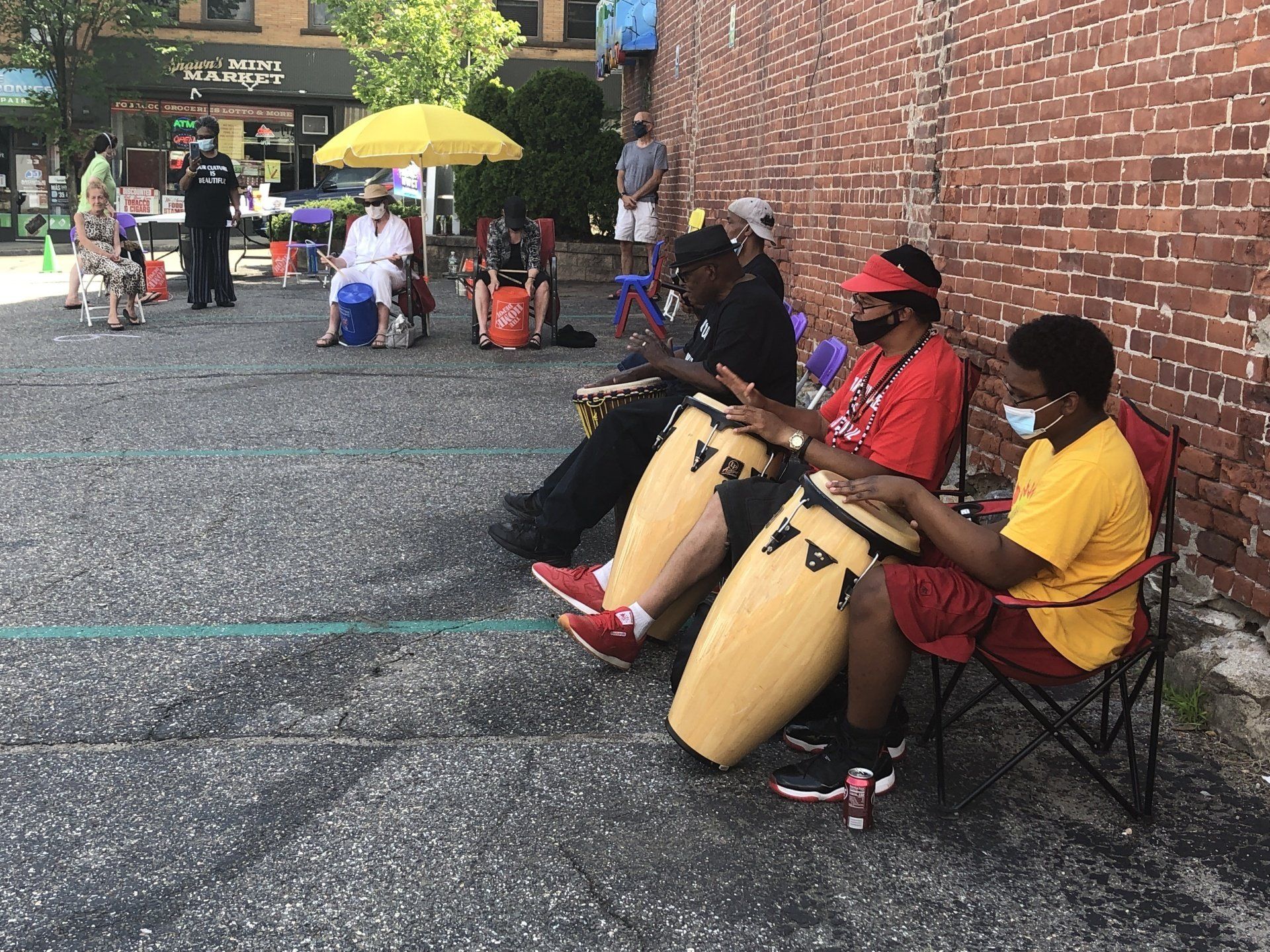 A group of people are sitting on the ground playing drums.