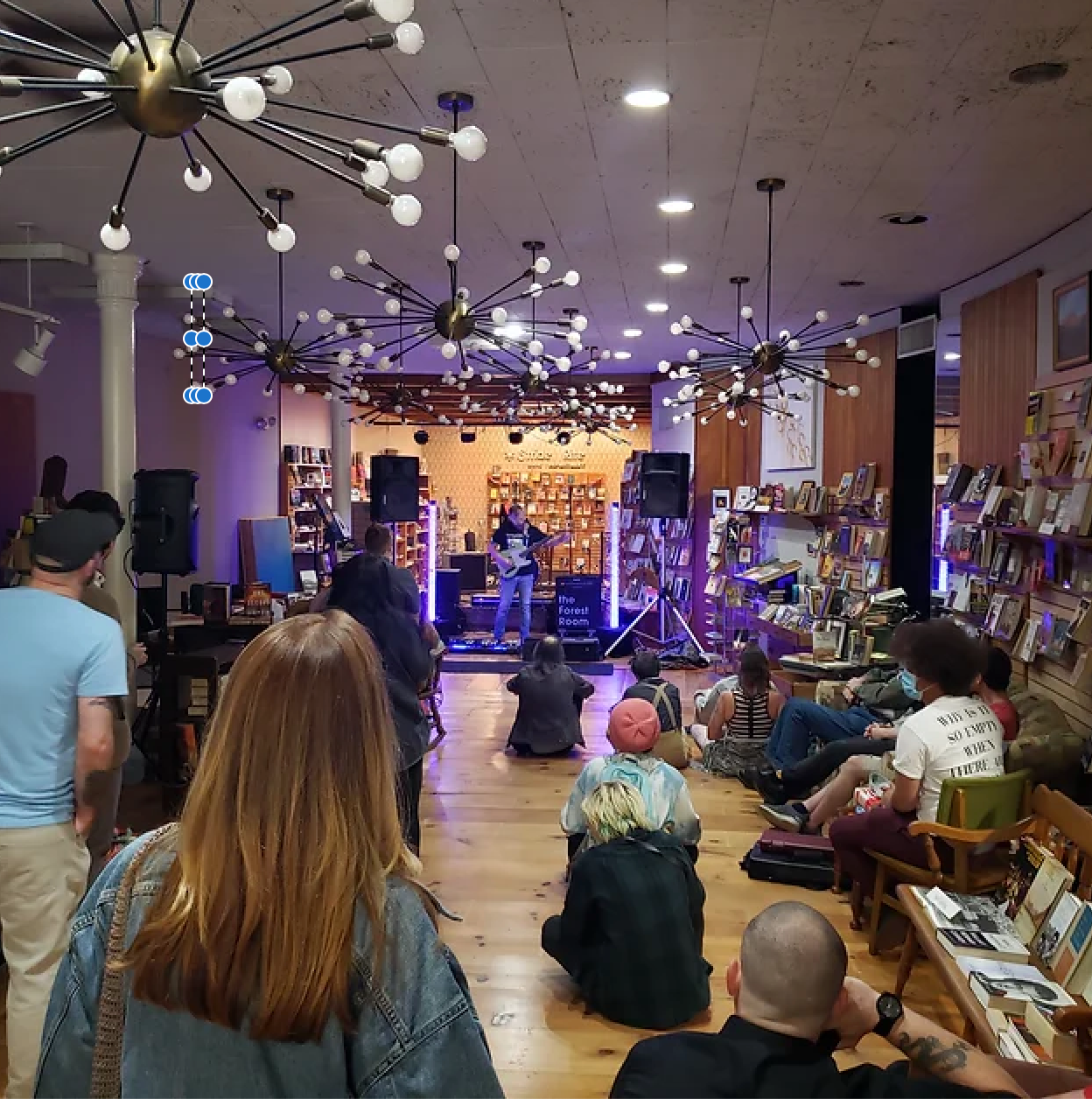 A group of people are gathered in a room with a band on stage