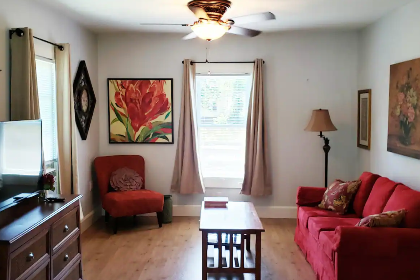 A living room with a red couch and a ceiling fan