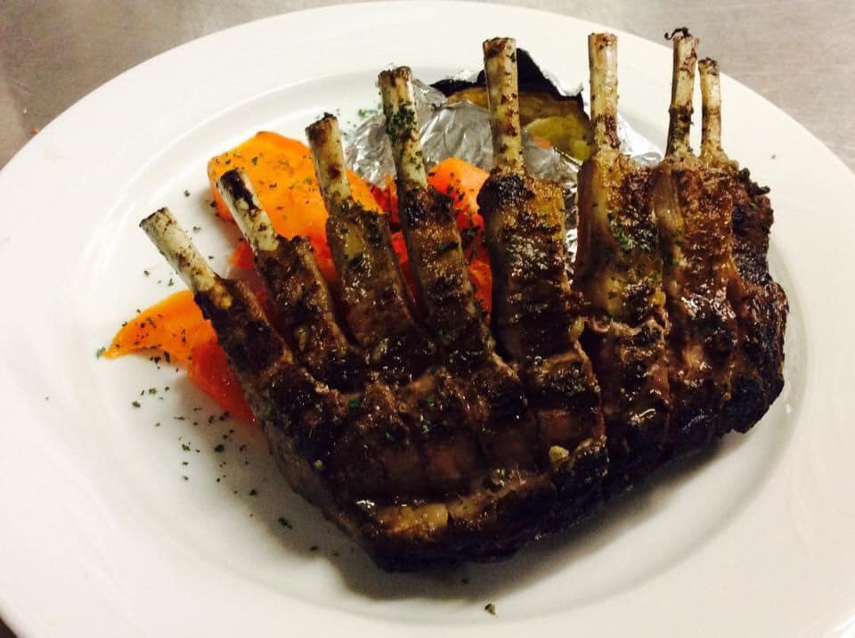 A white plate topped with lamb chops and carrots