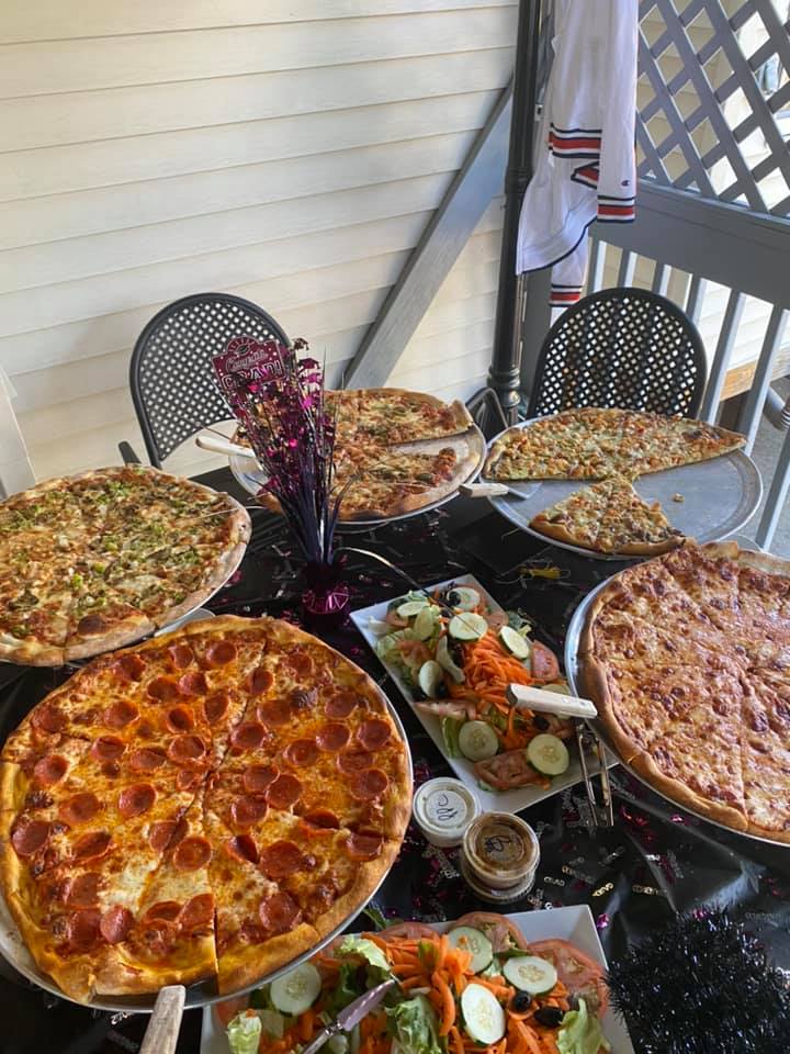 A table topped with a variety of pizzas and salads.