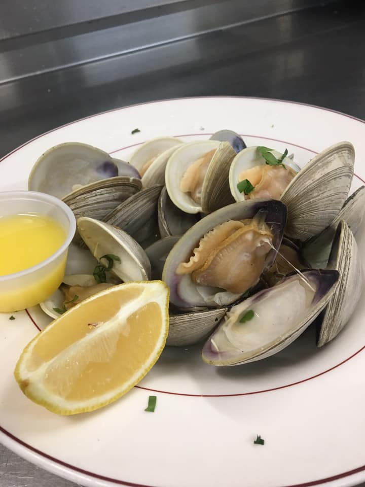 A white plate topped with clams and a slice of lemon.