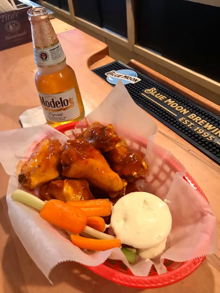 A basket of chicken wings and a bottle of modelos beer