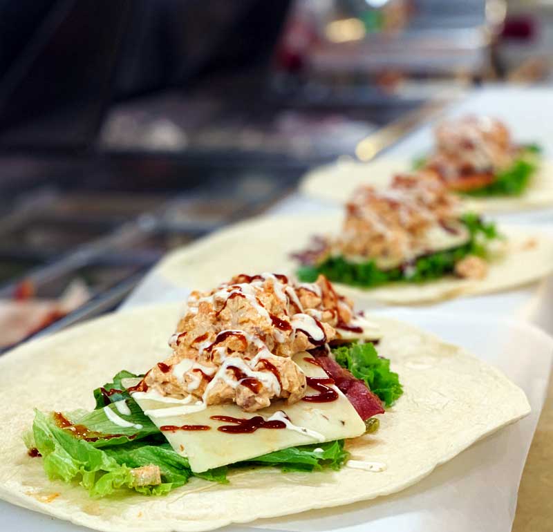 A close up of a tortilla with chicken and lettuce on a table