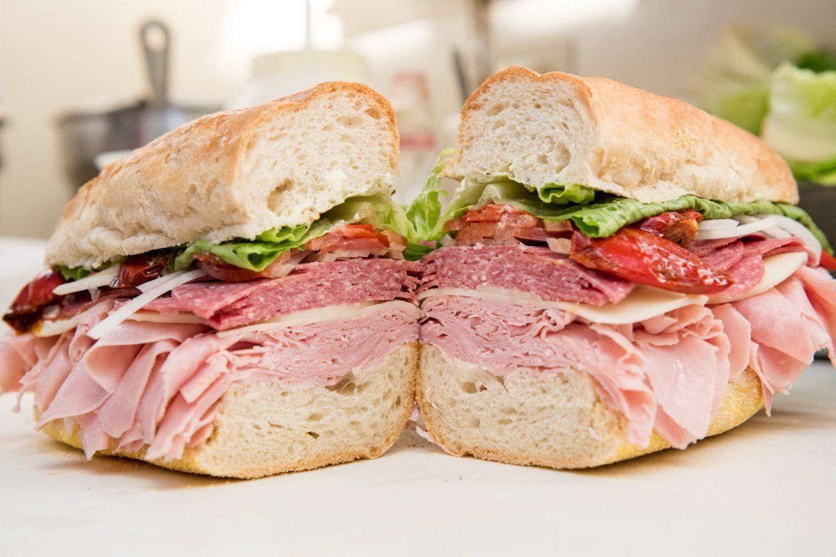 A sub sandwich is cut in half on a white plate.