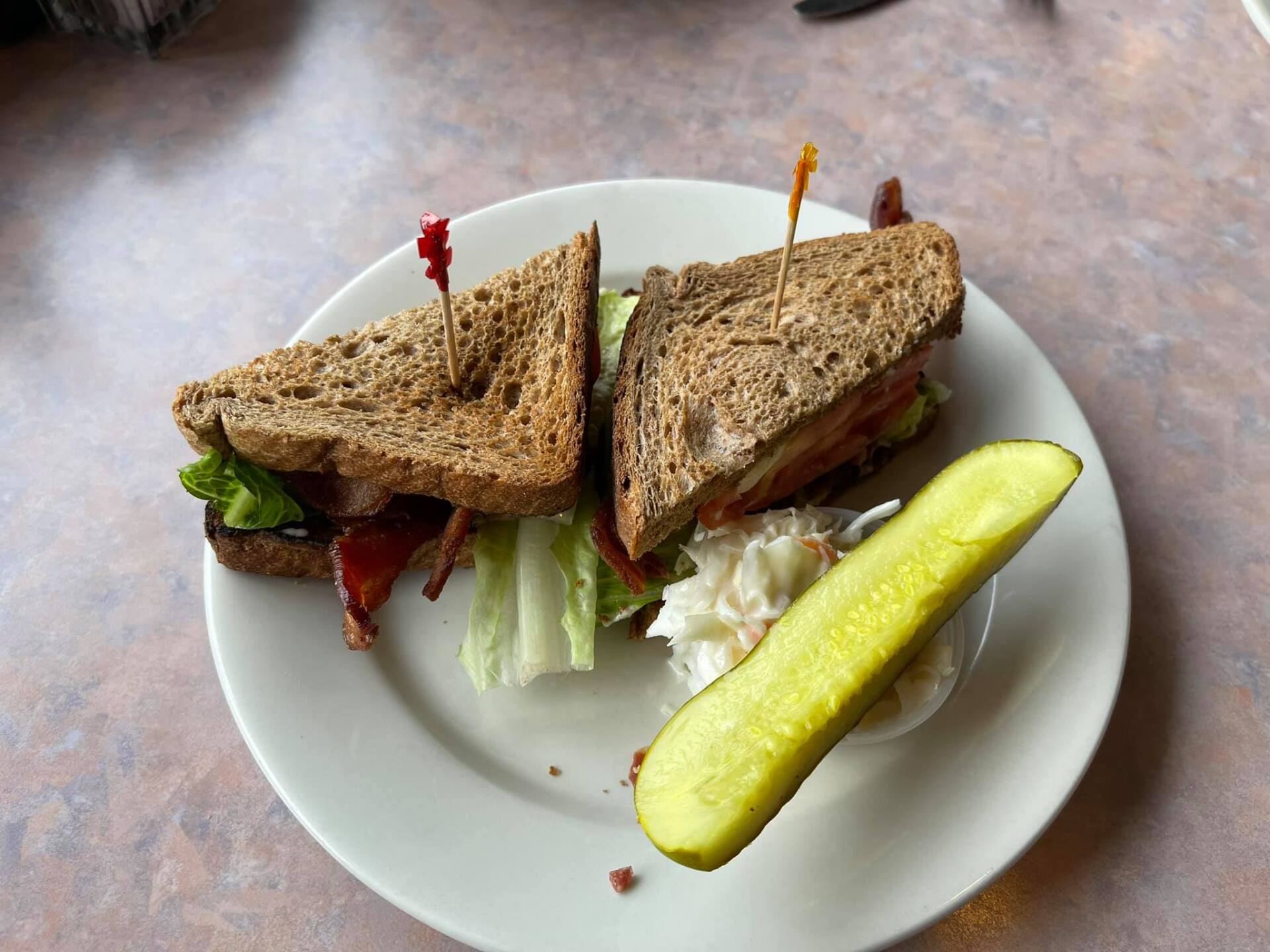 A white plate topped with a sandwich and a pickle