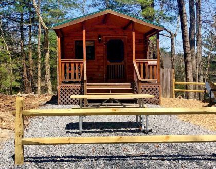 A small wooden cabin with a picnic table in front of it.
