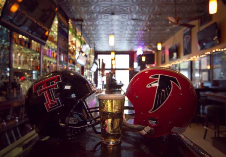 Two football helmets and a glass of beer on a table in a bar