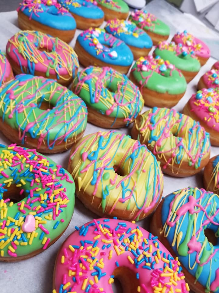 A bunch of donuts with different colored frosting and sprinkles