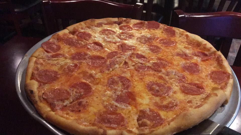 A pepperoni pizza is sitting on a pan on a table.