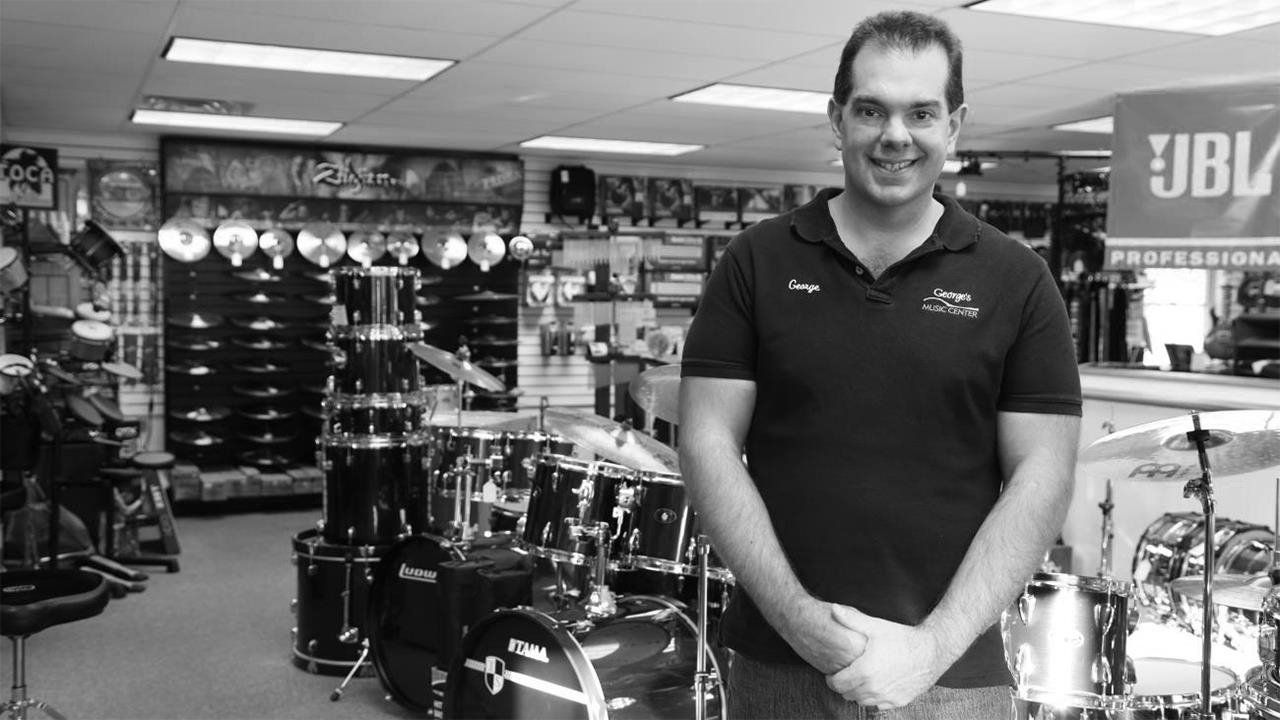 A man is standing in front of a drum set in a store.
