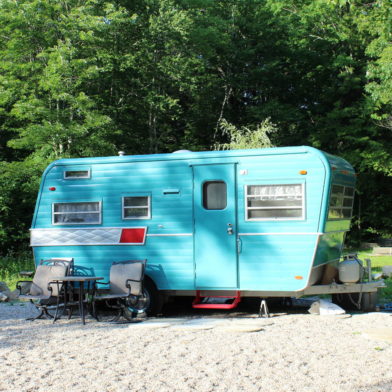 A blue trailer is parked in a gravel lot
