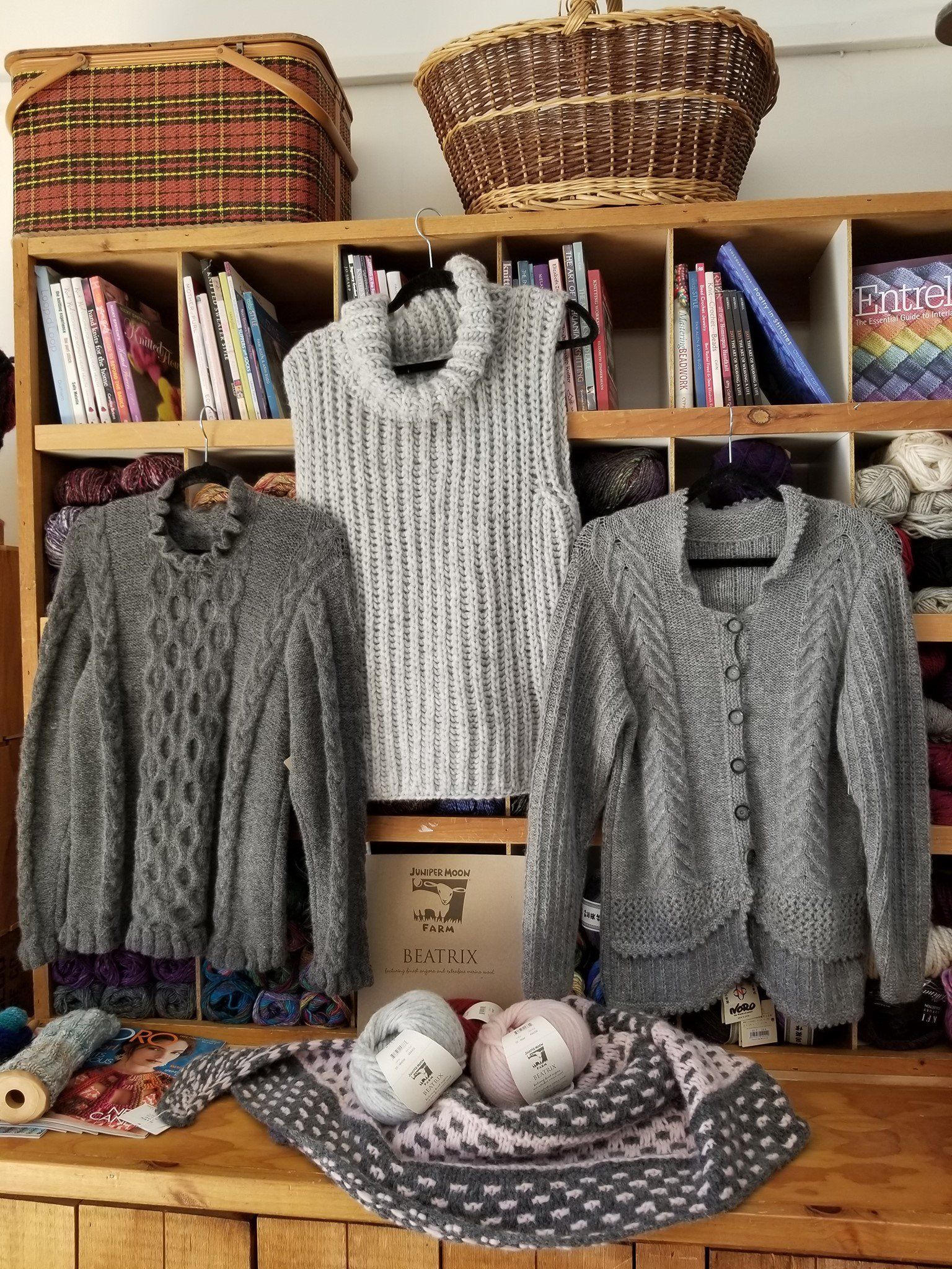 Three sweaters are sitting on top of a wooden table.