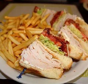 A white plate topped with a club sandwich and french fries.