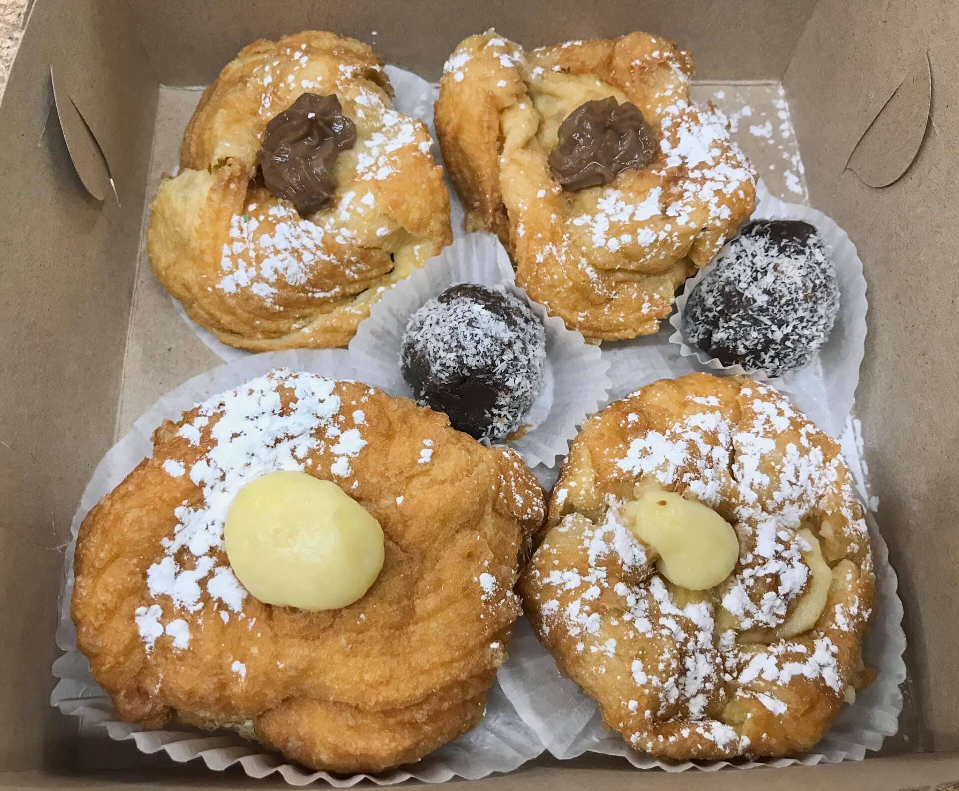 A box of donuts with powdered sugar on top