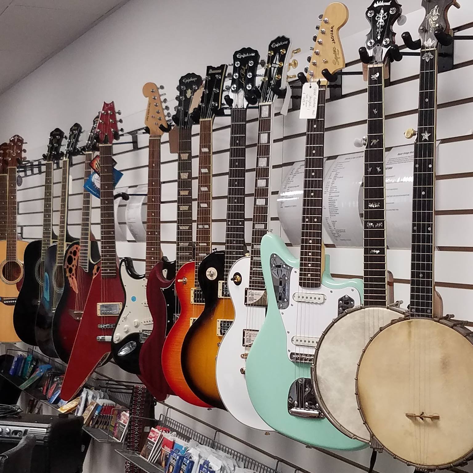 A bunch of guitars hanging on a wall in a store
