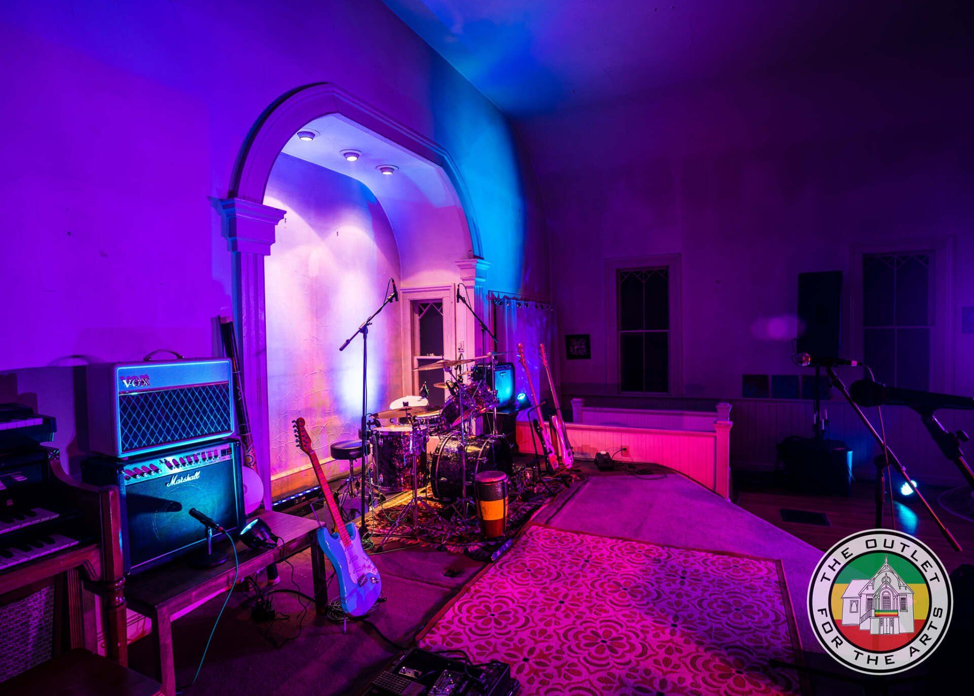 A room with purple lights and a drum set in it