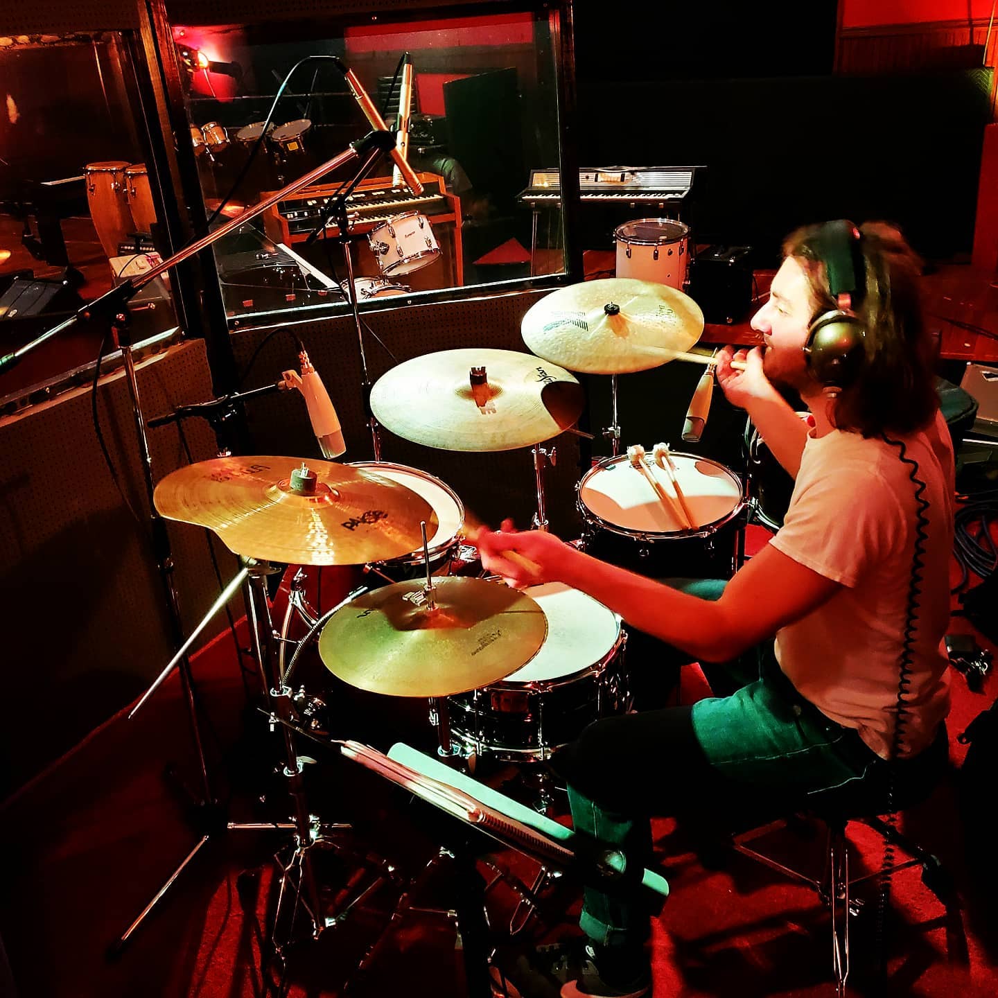 A man wearing headphones is playing drums in a dark room