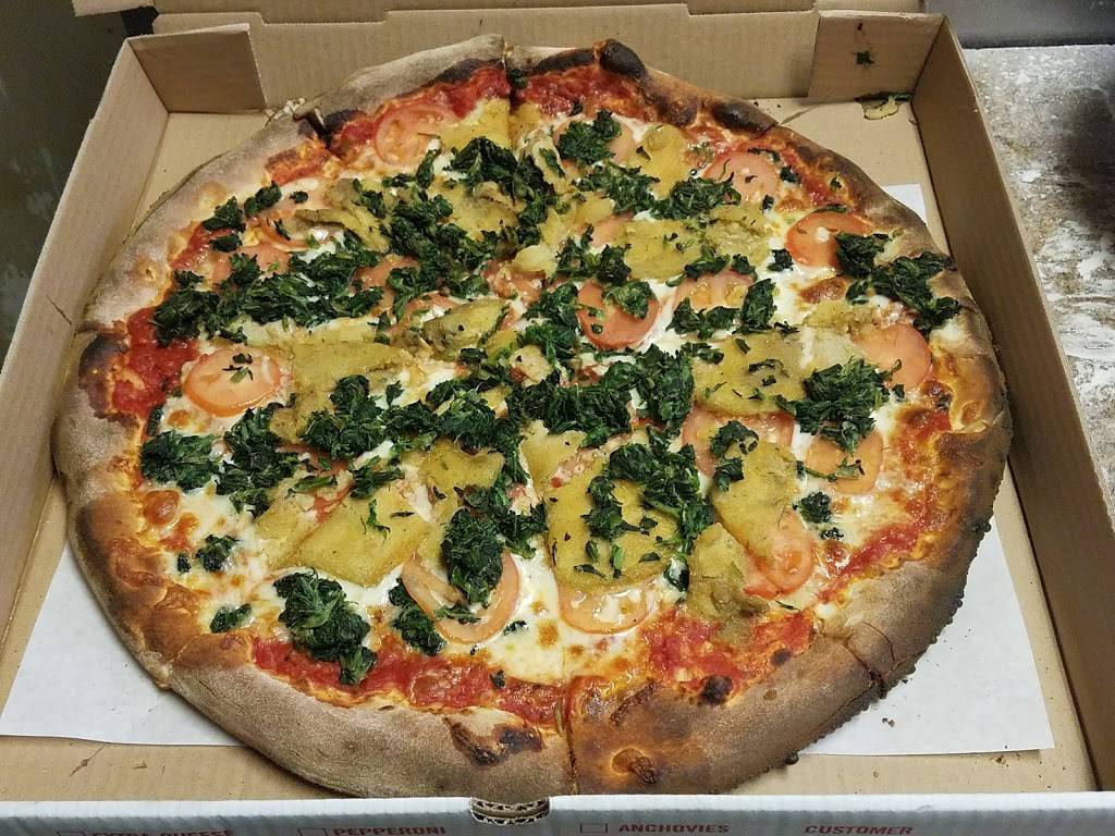 A pizza with pineapple and spinach is in a cardboard box