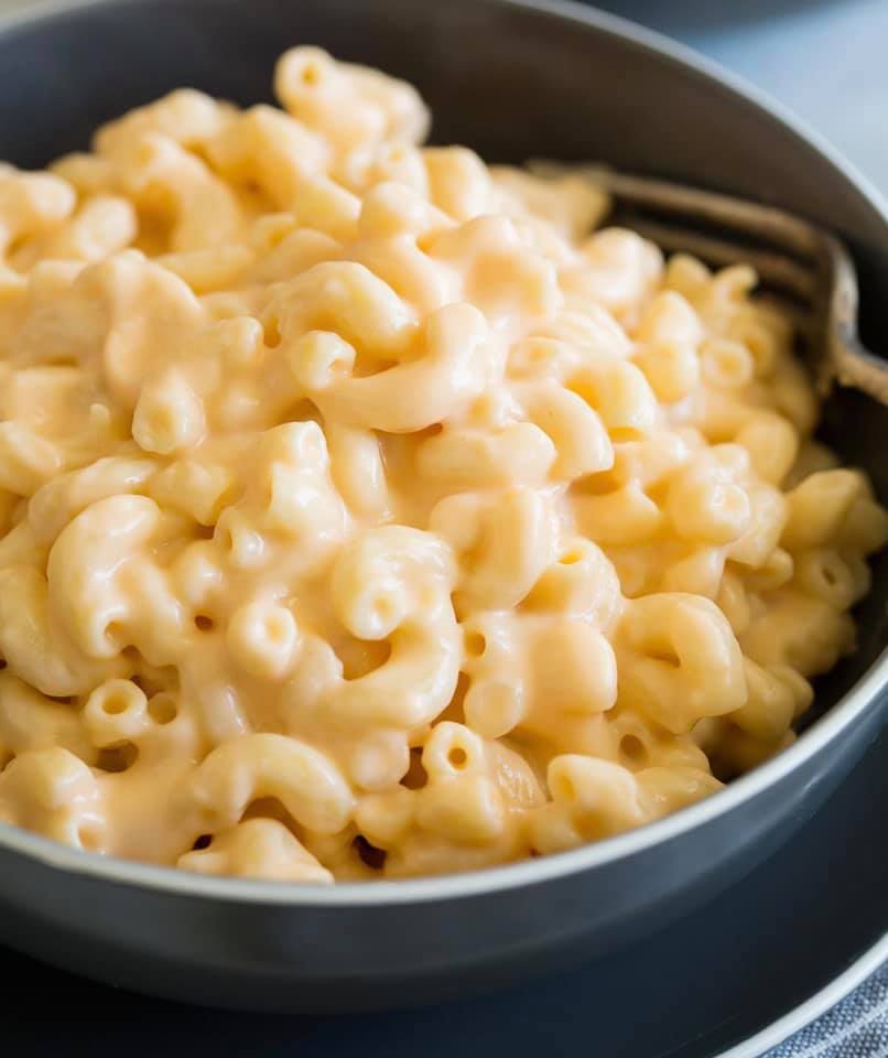 A bowl of macaroni and cheese with a fork in it.