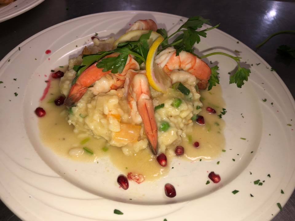 A white plate topped with shrimp and rice on a table.