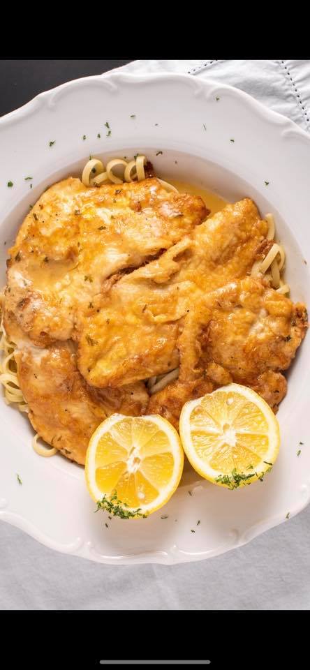 A white plate topped with chicken and noodles with lemon slices.