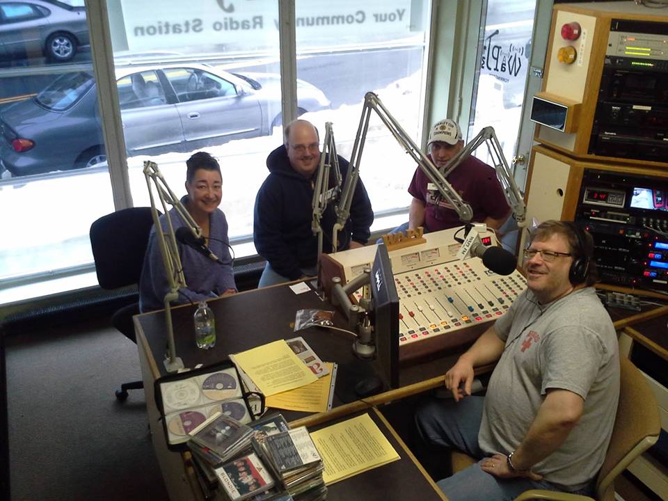 A group of people are sitting at a desk in a radio studio