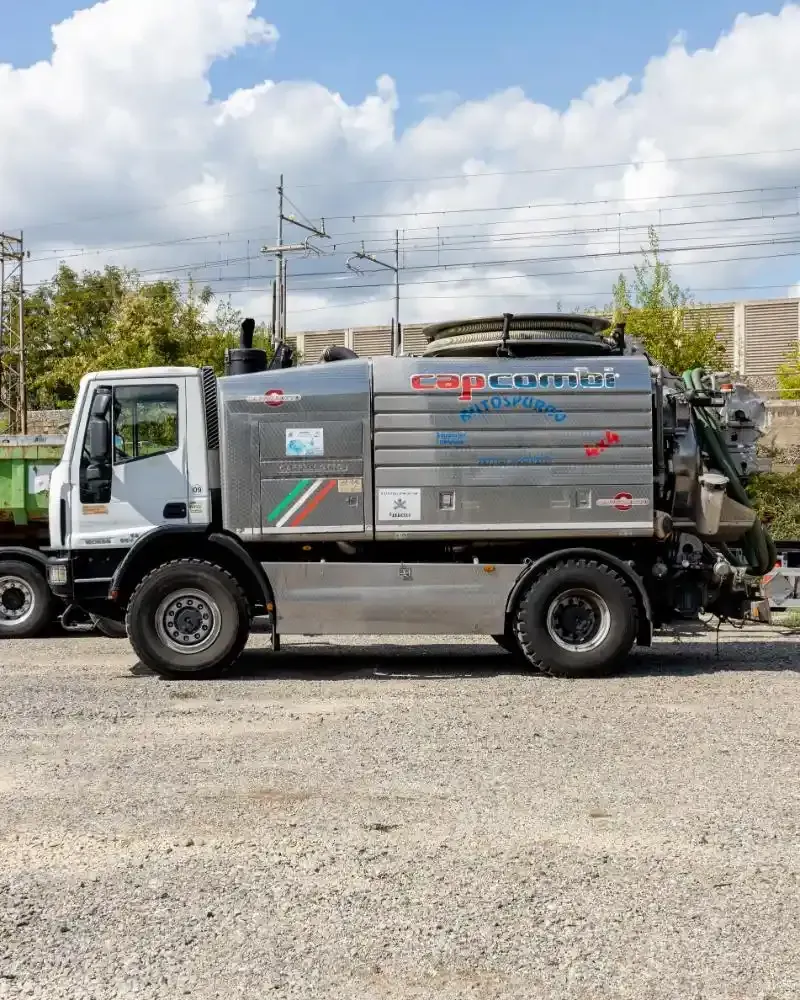 Un camion aspiratutto blu e bianco parcheggiato fuori da un edificio.