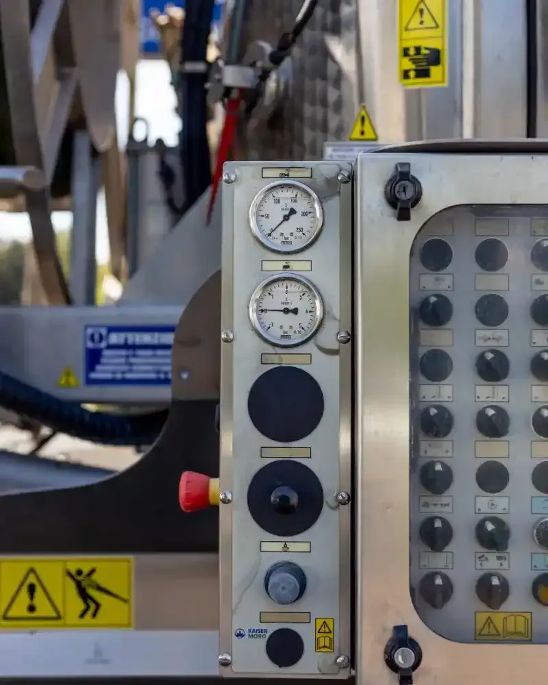 Macchina industriale blu con tubi flessibili a spirale e componenti metallici.