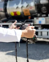 Un camion con fossa settica blu parcheggiato davanti a un edificio beige, con un tubo flessibile teso.