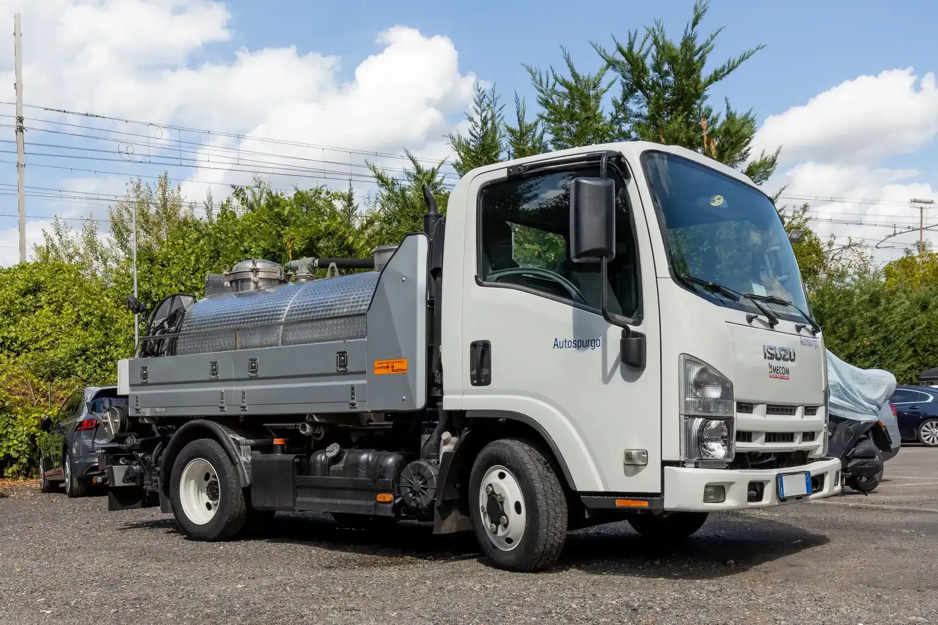 Un camion della nettezza urbana blu e bianco parcheggiato accanto a un edificio beige chiaro.