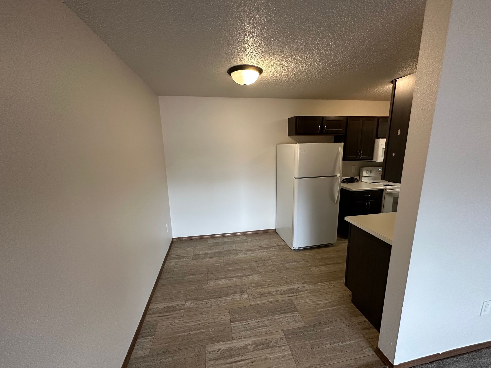 An empty kitchen with a refrigerator and a stove.