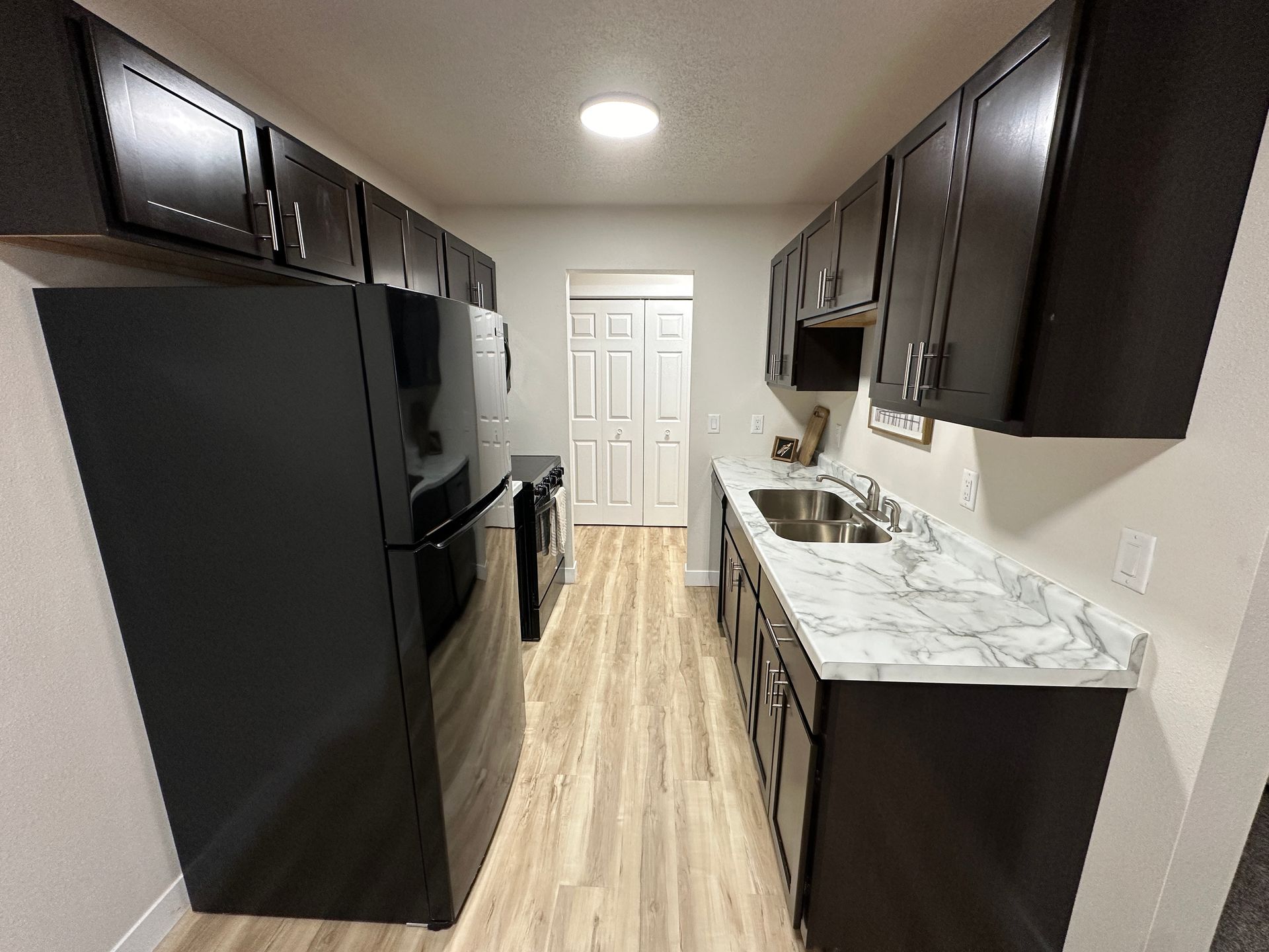 A kitchen with black cabinets and a black refrigerator