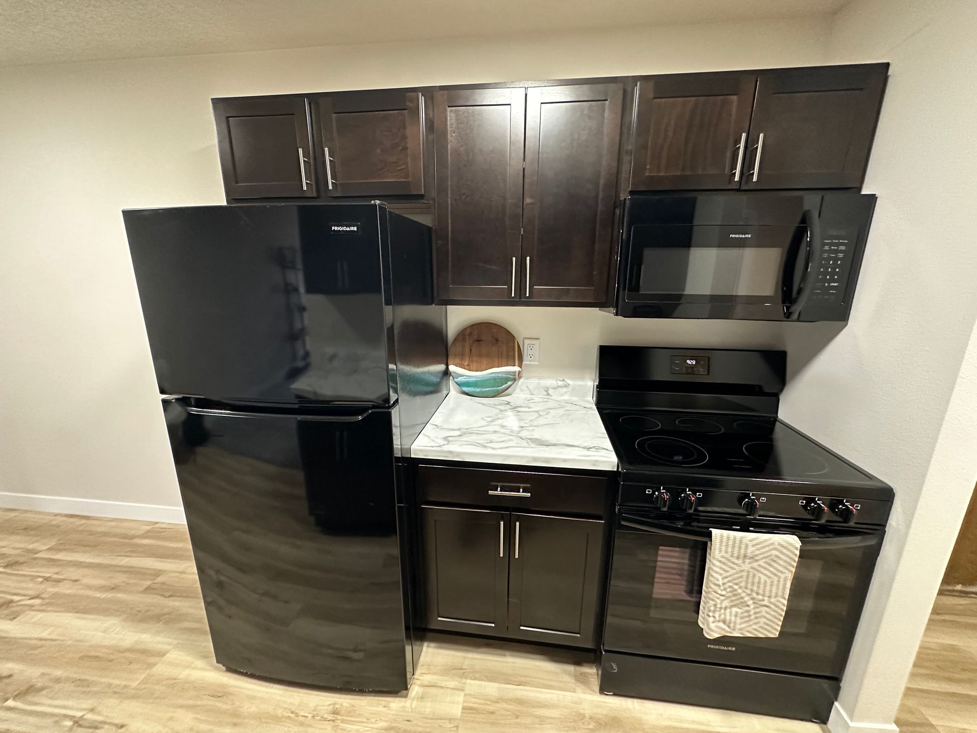 A kitchen with a refrigerator , stove , microwave and cabinets.