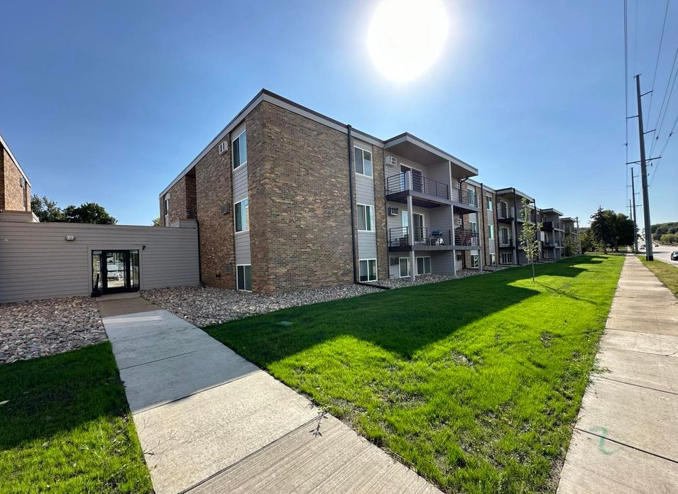 A large apartment building with a sidewalk in front of it.