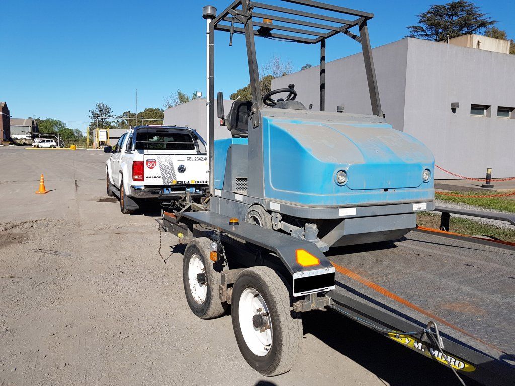 Un camión está remolcando un vehículo azul en un remolque.