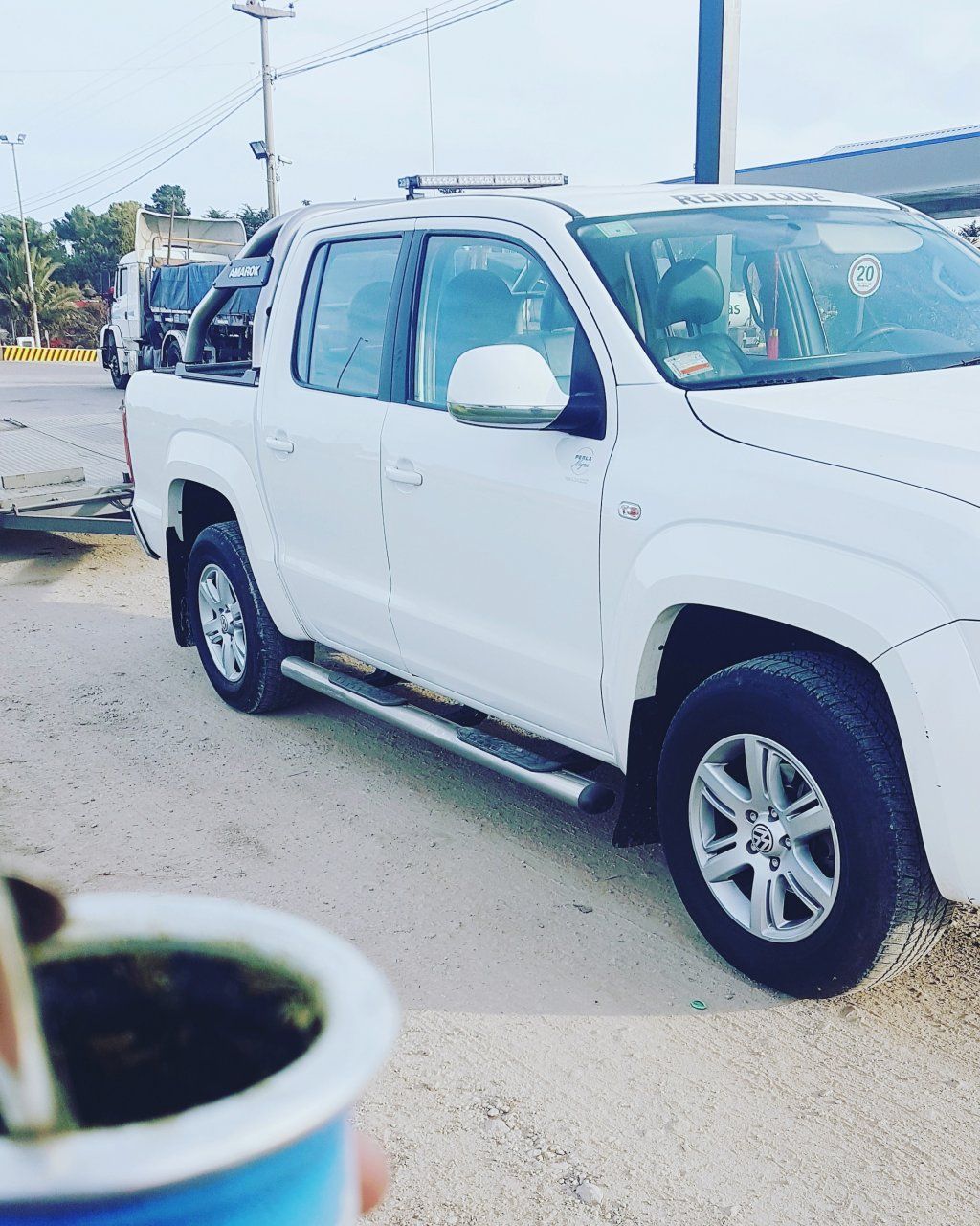 Un camión blanco está estacionado al lado de una taza azul.