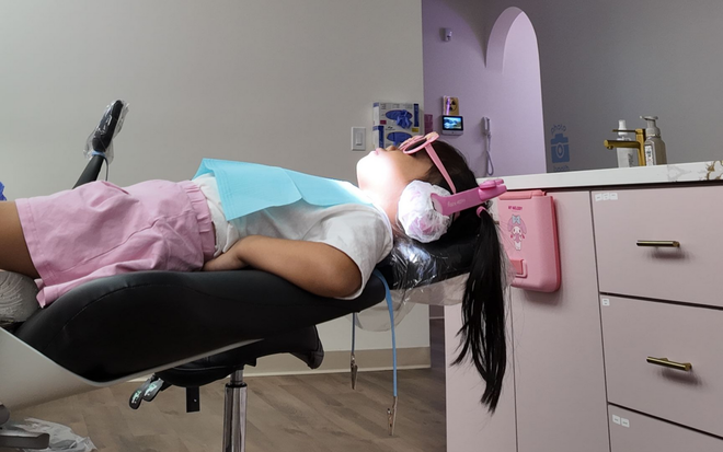 Dentist showing a tool to a child patient in a dental office.