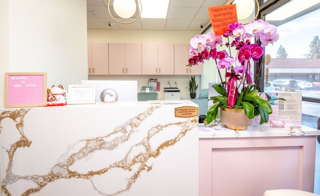 Smiling child in a white shirt, blurred classroom background with colorful decorations.