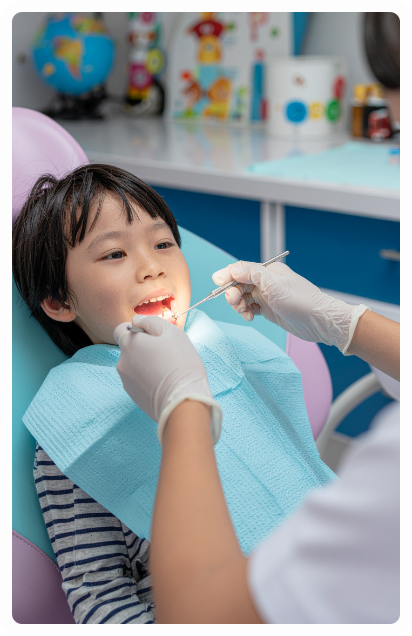 Boy in dentist chair with mouth open, receiving dental checkup.