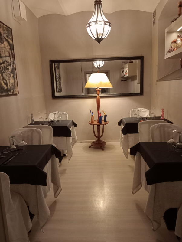 Una sala da pranzo con tavoli, sedie e una lampada