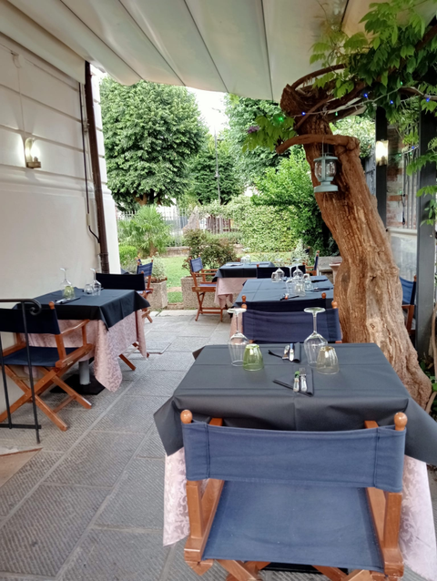 Un patio con tavoli e sedie e un albero sullo sfondo