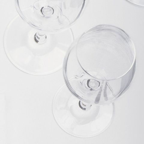 Tre bicchieri di vino sono appoggiati su un tavolo bianco.