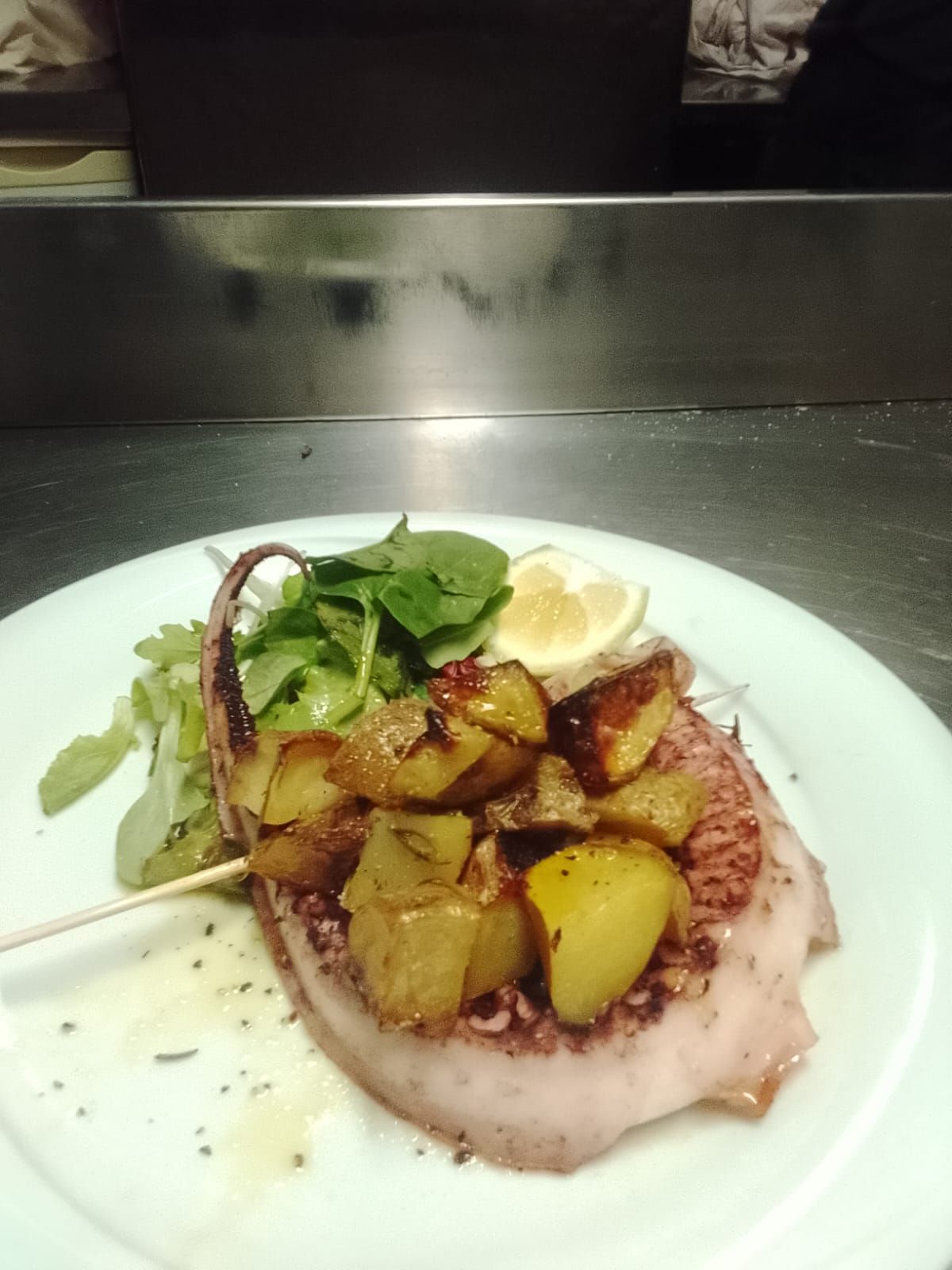Un piatto bianco con carne, patate e lattuga