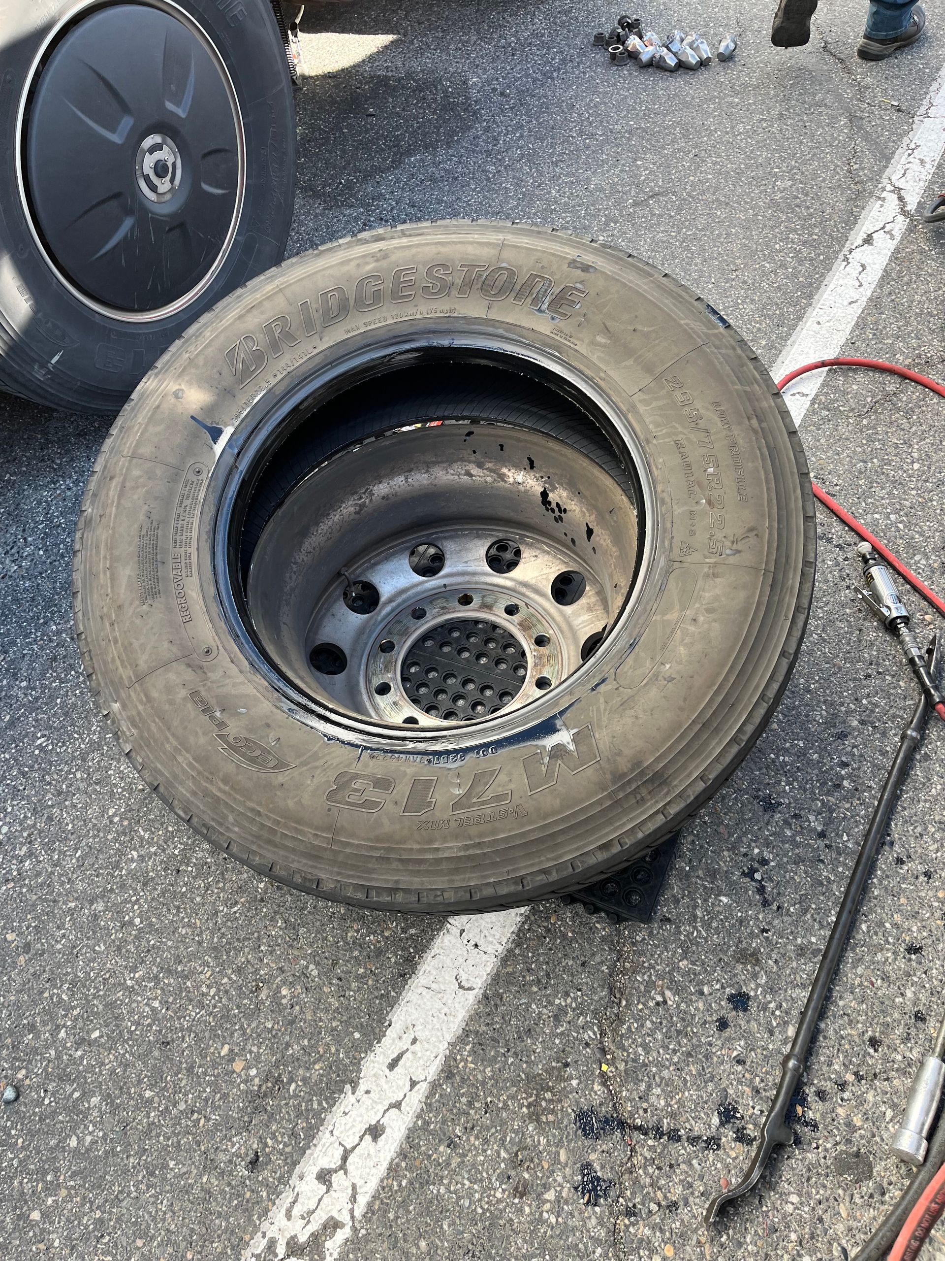 A tire with a hole in it is sitting on the ground.