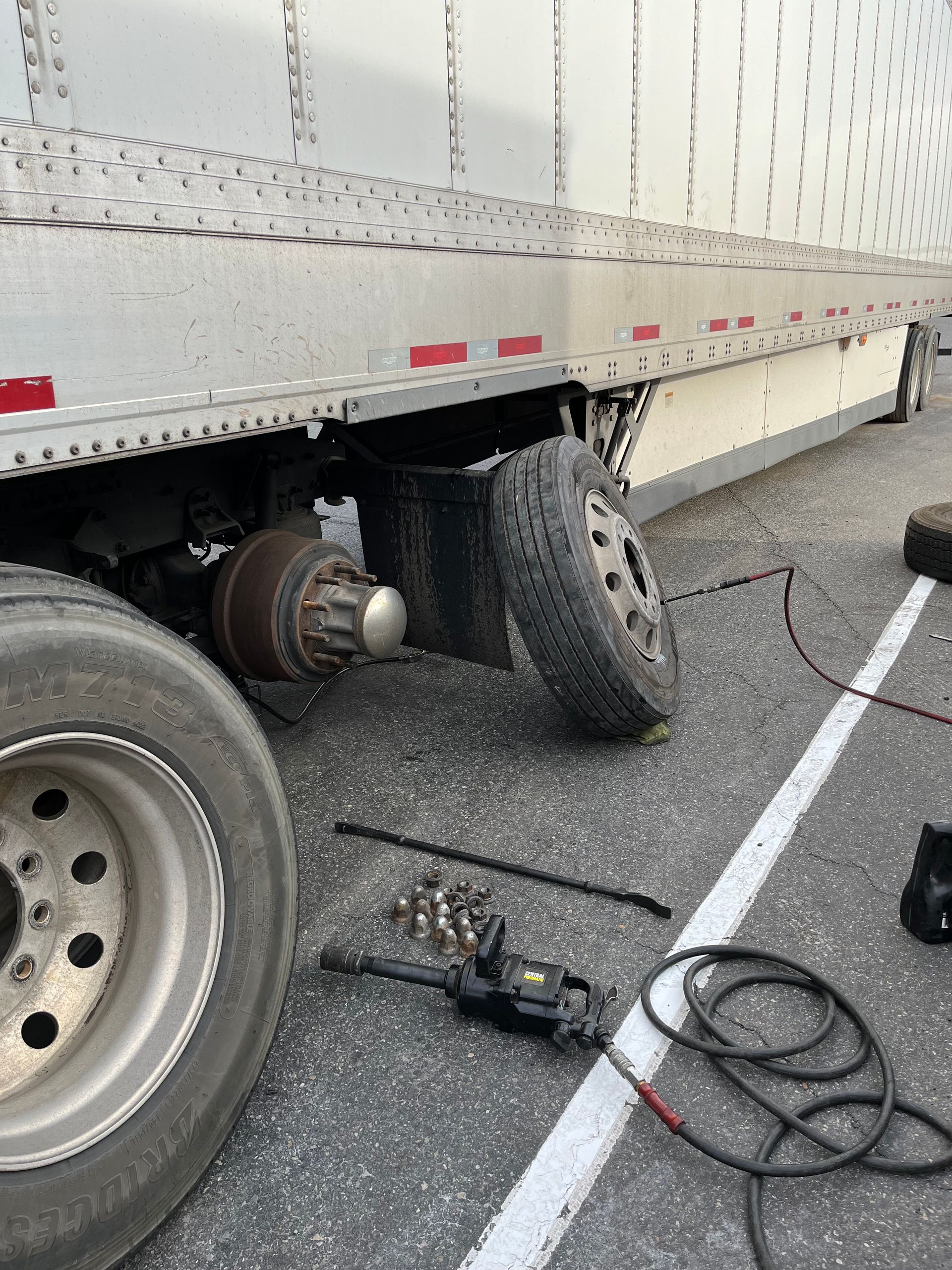 A truck with a flat tire is sitting on the side of the road.