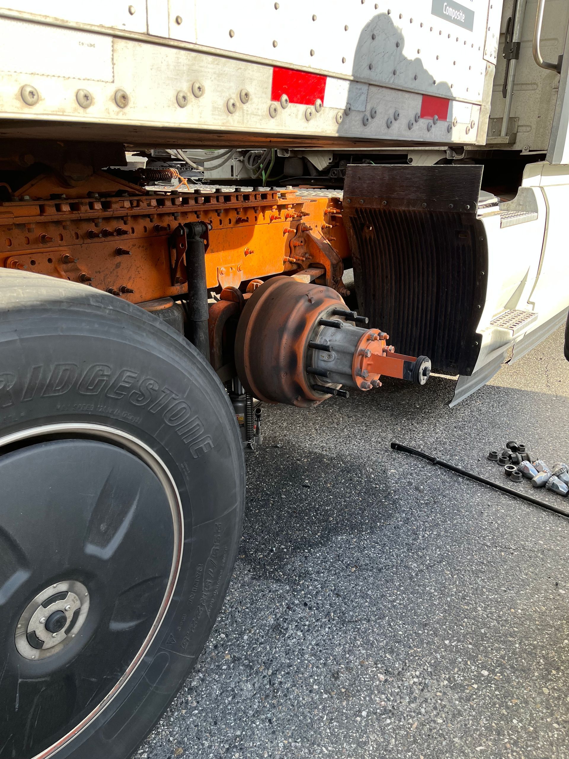 A truck is sitting on the side of the road with a tire on it.