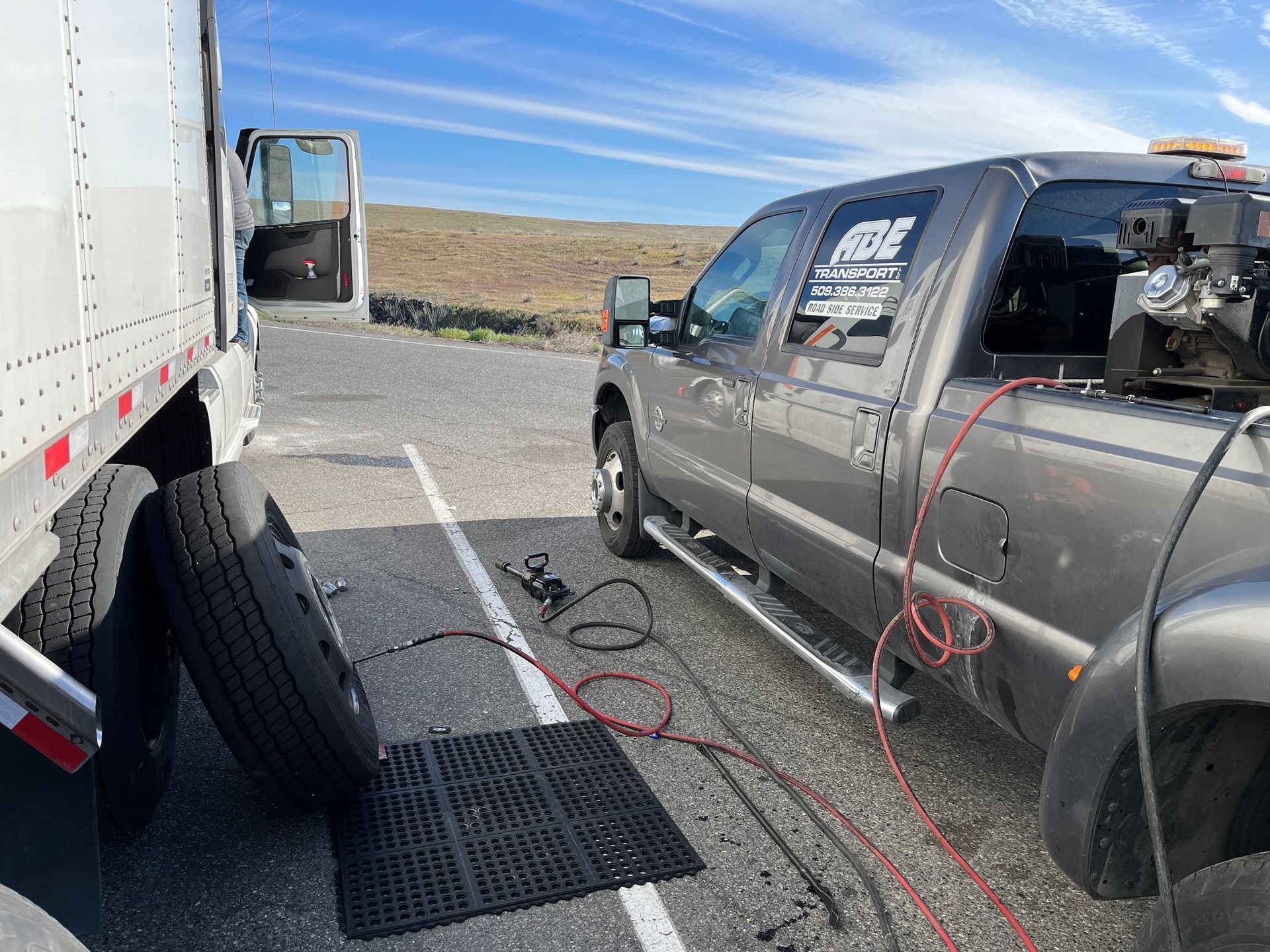 A truck is sitting in a parking lot next to a trailer.