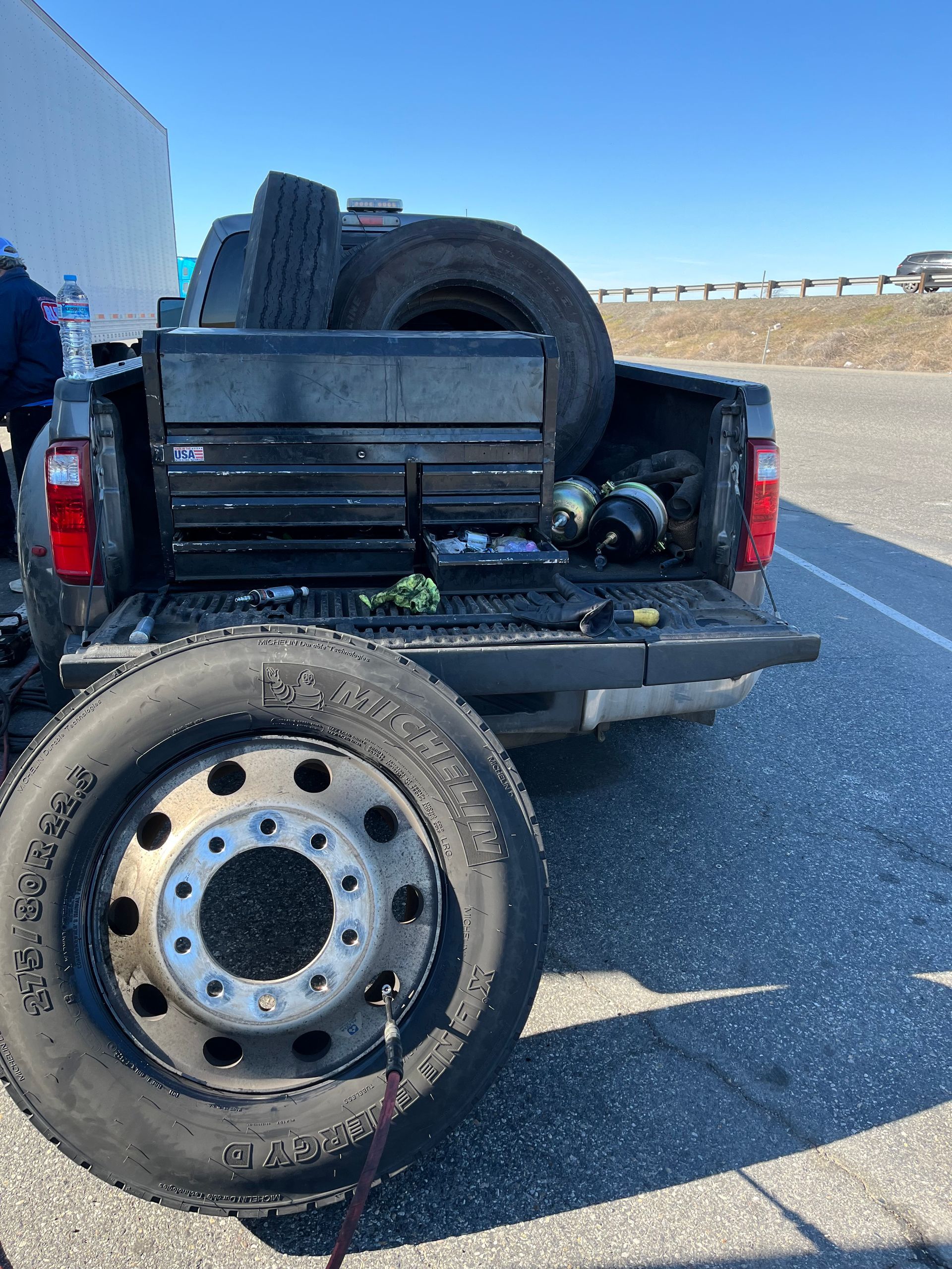A truck with a tire in the back is parked on the side of the road.