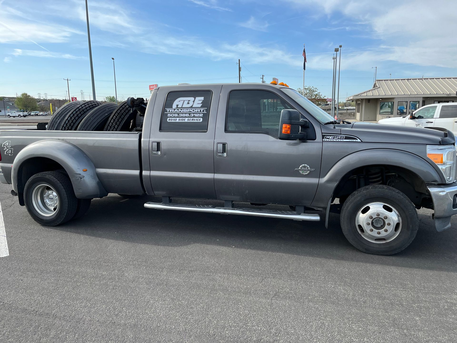 A gray pickup truck with tires on the back is parked in a parking lot.